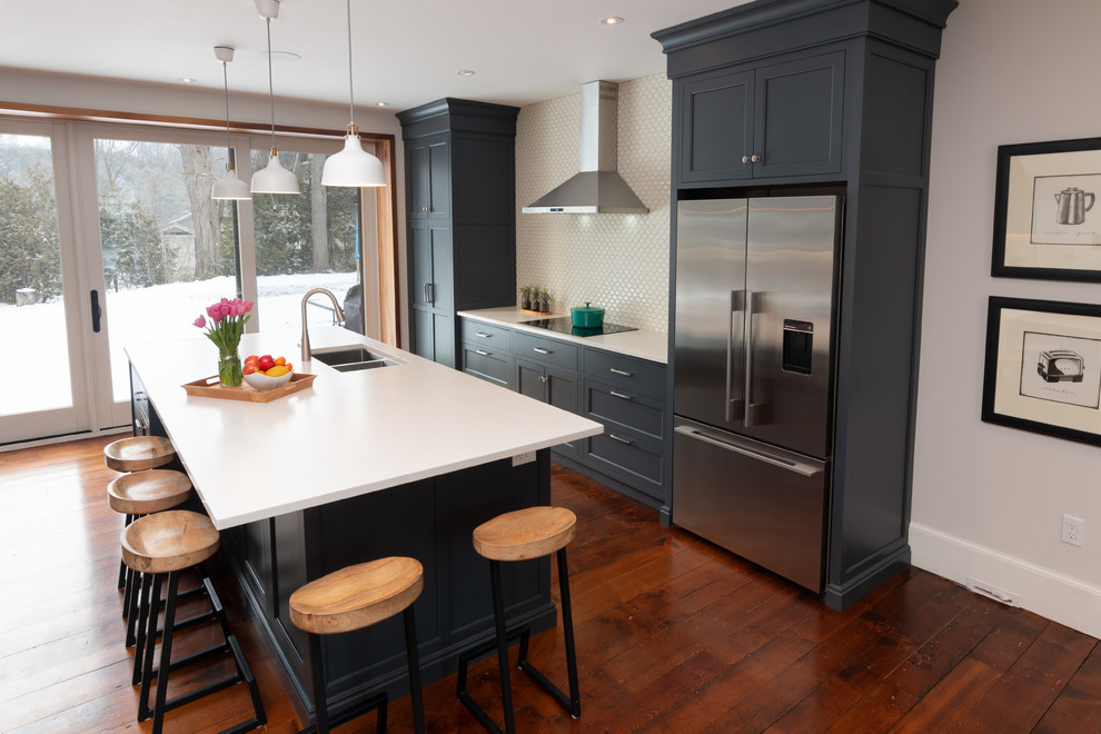 Inspiration for a large traditional kitchen in Toronto with a double-bowl sink, shaker cabinets, blue cabinets, engineered stone countertops, beige splashback, porcelain splashback, stainless steel appliances, medium hardwood flooring, an island, brown floors and white worktops.