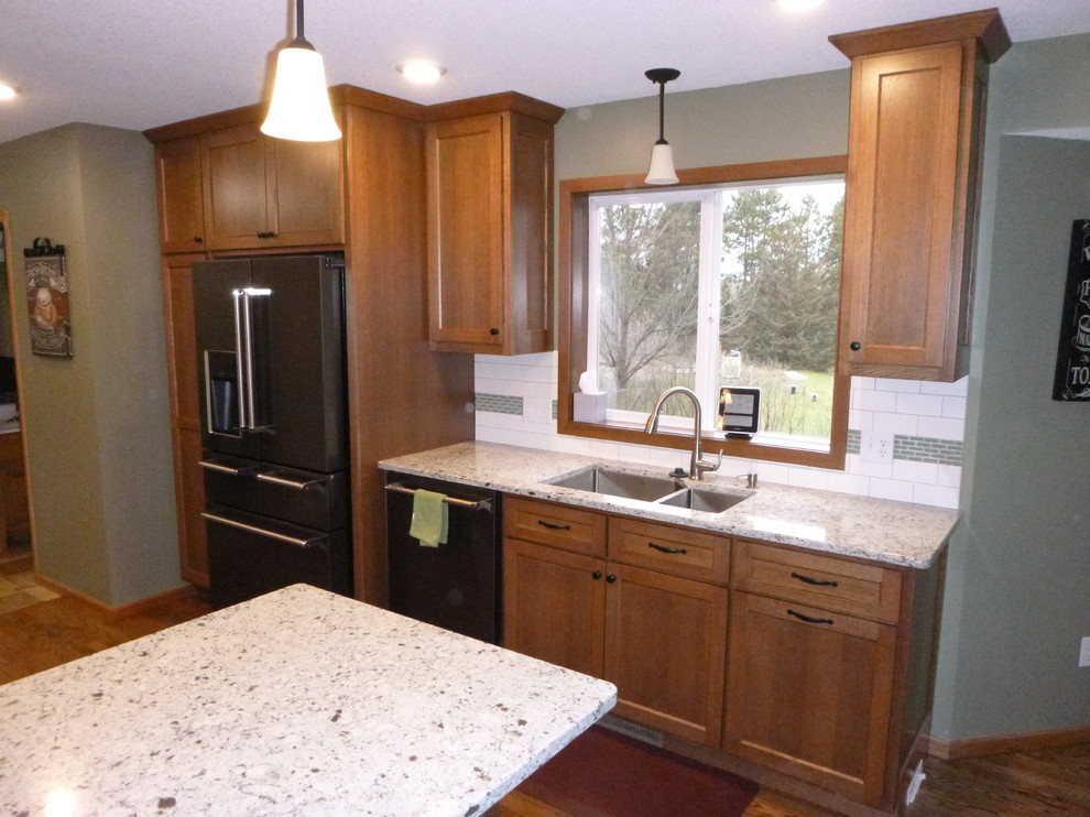 Exempel på ett mellanstort klassiskt kök, med en undermonterad diskho, släta luckor, skåp i mörkt trä, granitbänkskiva, gult stänkskydd, stänkskydd i keramik, svarta vitvaror, mörkt trägolv och en halv köksö