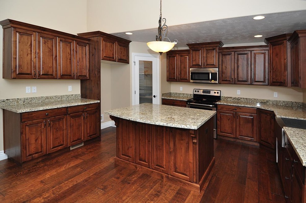 Inspiration for a large craftsman u-shaped dark wood floor eat-in kitchen remodel in Salt Lake City with a farmhouse sink, raised-panel cabinets, distressed cabinets, granite countertops, stone tile backsplash, stainless steel appliances and an island