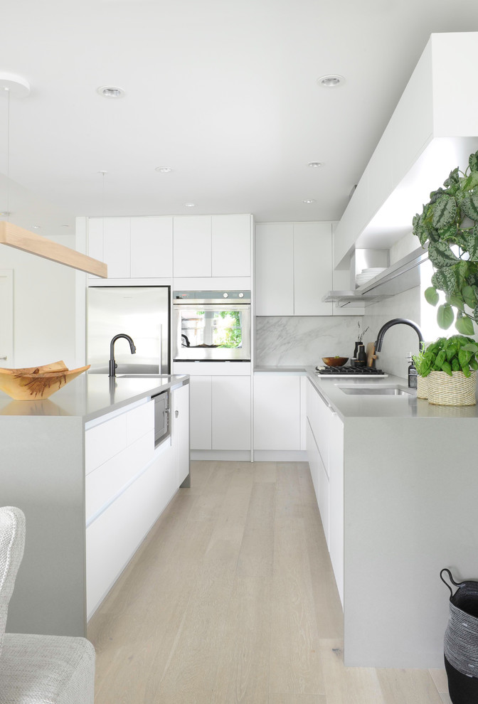 Example of a mid-sized danish light wood floor open concept kitchen design in Vancouver with flat-panel cabinets, white cabinets, quartz countertops, stone slab backsplash, an island and gray countertops