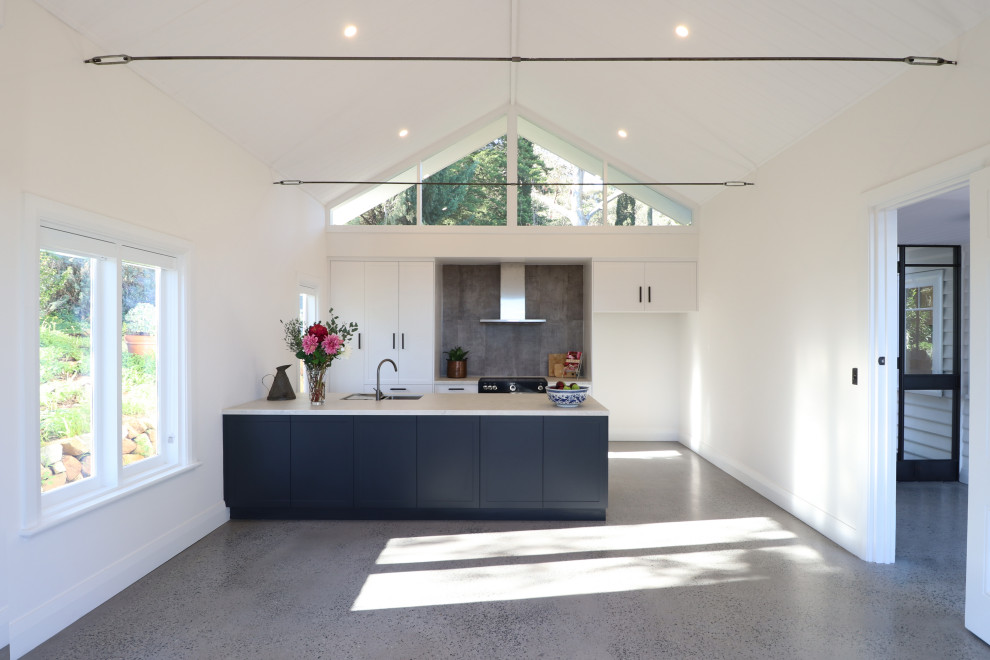 Bild på ett mellanstort vintage grå grått kök och matrum, med en undermonterad diskho, luckor med infälld panel, grått stänkskydd, stänkskydd i porslinskakel, svarta vitvaror, betonggolv, en köksö och grått golv
