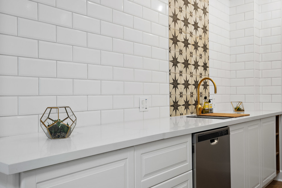 Klassisk inredning av ett mellanstort vit vitt kök, med en undermonterad diskho, luckor med upphöjd panel, vita skåp, bänkskiva i kvarts, vitt stänkskydd, stänkskydd i keramik, rostfria vitvaror, laminatgolv och brunt golv