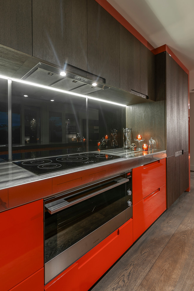 Inspiration för ett mellanstort funkis brun linjärt brunt kök och matrum, med en undermonterad diskho, släta luckor, orange skåp, bänkskiva i koppar, svart stänkskydd, glaspanel som stänkskydd, svarta vitvaror, mörkt trägolv, en köksö och brunt golv