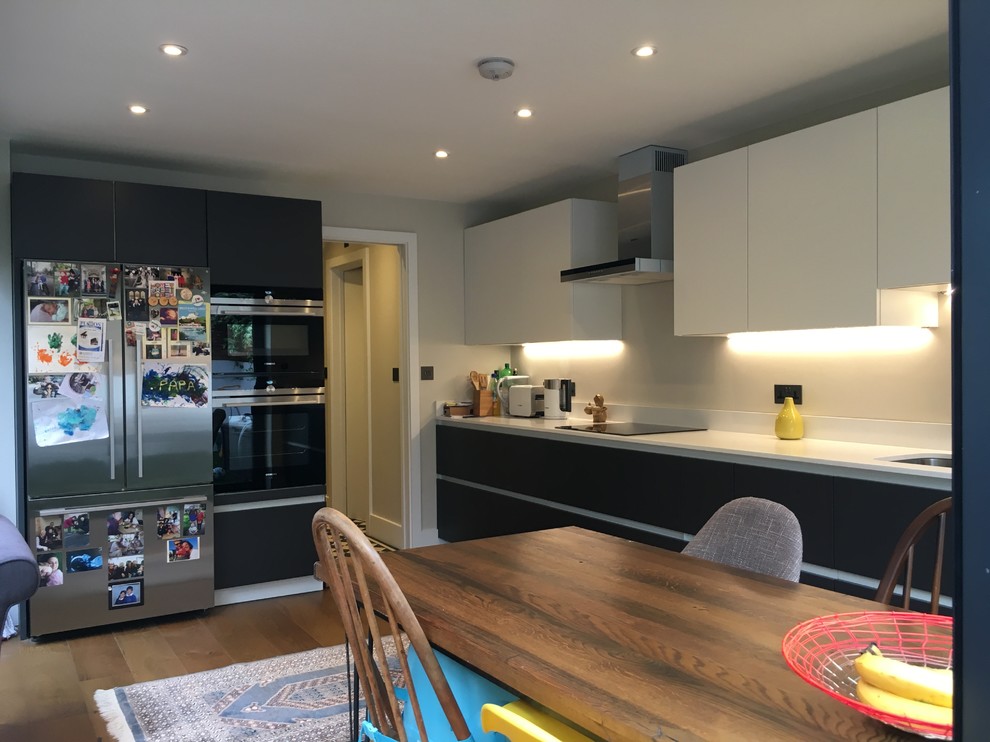 Inspiration for a medium sized contemporary l-shaped open plan kitchen in London with a double-bowl sink, flat-panel cabinets, quartz worktops, medium hardwood flooring and no island.