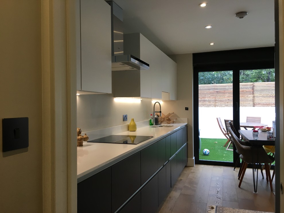Photo of a medium sized contemporary l-shaped open plan kitchen in London with a double-bowl sink, flat-panel cabinets, quartz worktops, medium hardwood flooring and no island.