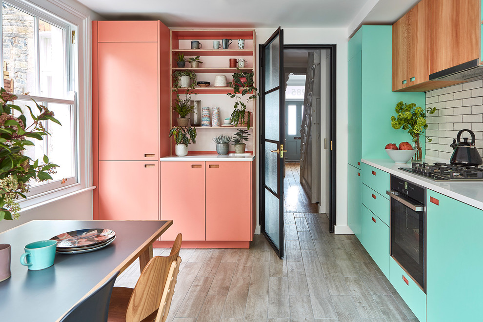 Inspiration for a medium sized scandi l-shaped kitchen/diner in London with a submerged sink, flat-panel cabinets, turquoise cabinets, composite countertops, white splashback, metro tiled splashback, integrated appliances, porcelain flooring, no island, grey floors and white worktops.