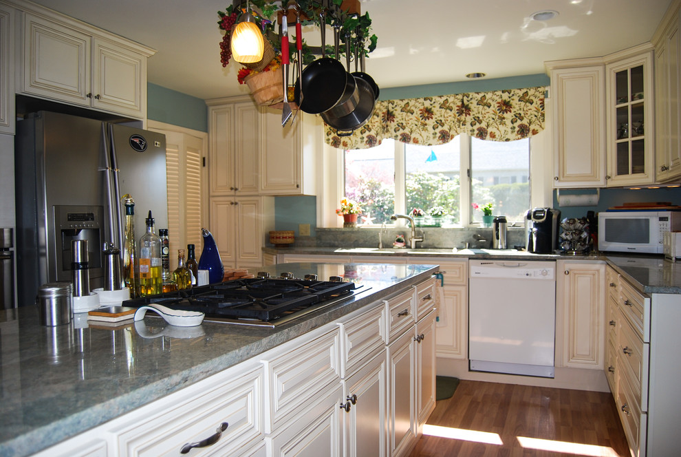 Immagine di una cucina classica con ante con bugna sagomata, ante bianche, top in granito, elettrodomestici in acciaio inossidabile e pavimento in legno massello medio
