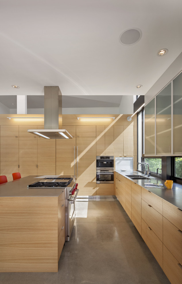 This is an example of a large modern galley kitchen pantry in Denver with a double-bowl sink, flat-panel cabinets, beige cabinets, stainless steel appliances, concrete flooring, an island and grey floors.