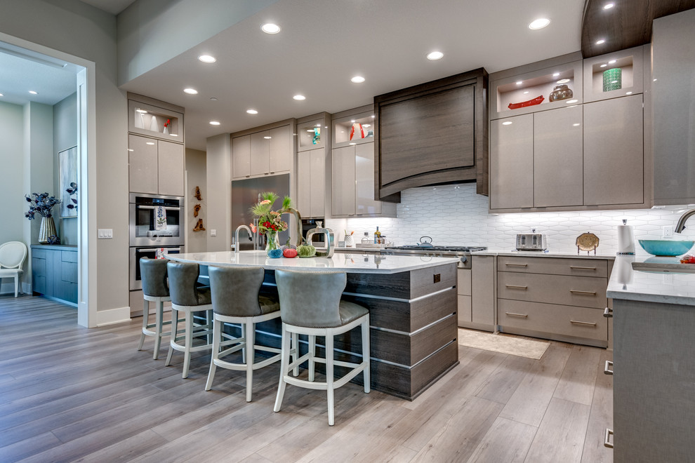 Example of a trendy u-shaped gray floor kitchen design in Portland with an undermount sink, flat-panel cabinets, gray cabinets, white backsplash, stainless steel appliances, an island and white countertops