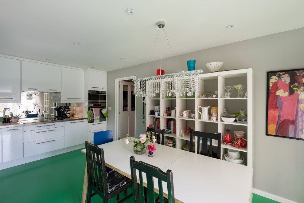 Idéer för att renovera ett mellanstort funkis kök, med en nedsänkt diskho, släta luckor, vita skåp, laminatbänkskiva, stänkskydd med metallisk yta, spegel som stänkskydd, rostfria vitvaror, linoleumgolv och grönt golv