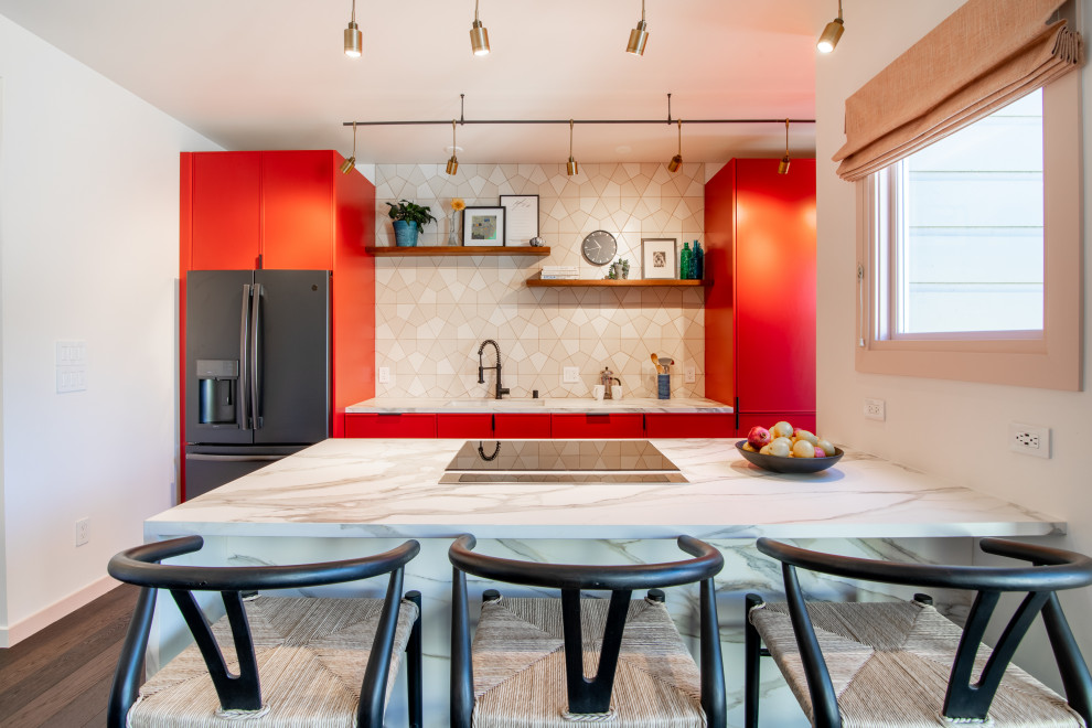 Modern inredning av ett stort vit linjärt vitt kök och matrum, med röda skåp, marmorbänkskiva, vitt stänkskydd, stänkskydd i keramik, mellanmörkt trägolv, en köksö och brunt golv