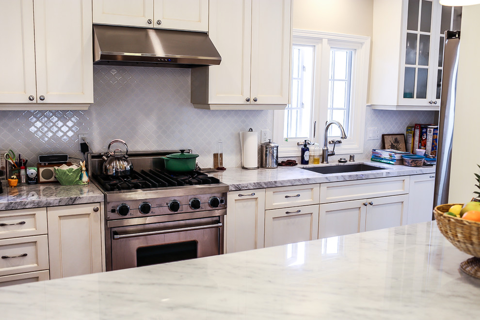 Bild på ett stort rustikt linjärt kök och matrum, med en nedsänkt diskho, luckor med upphöjd panel, vita skåp, bänkskiva i kvarts, blått stänkskydd, stänkskydd i porslinskakel, rostfria vitvaror, mörkt trägolv och en halv köksö
