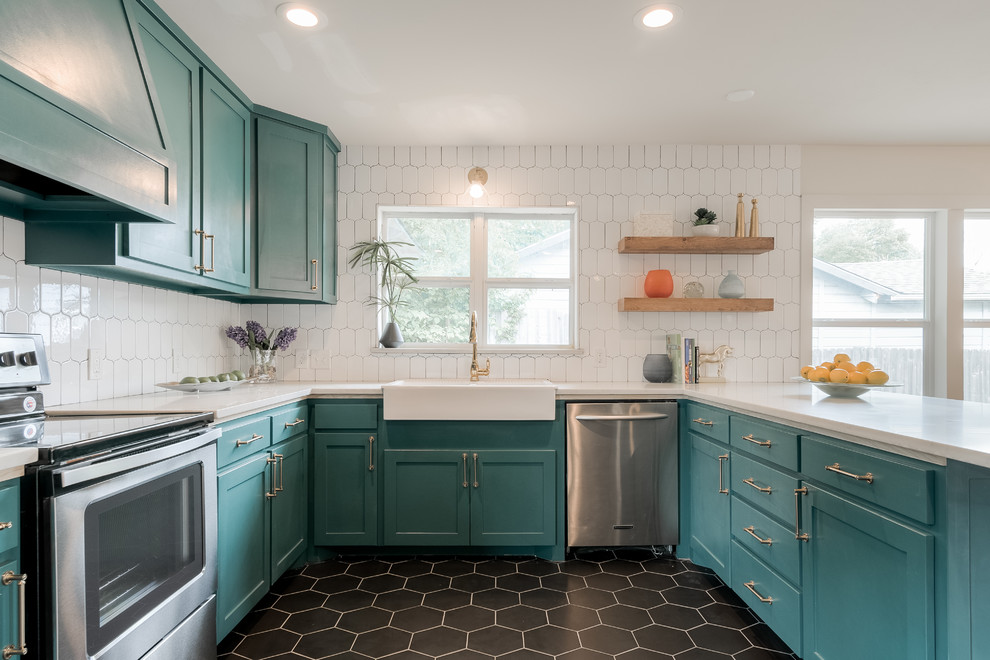 Expansive retro u-shaped kitchen in Dallas with a belfast sink, shaker cabinets, blue cabinets, white splashback, stainless steel appliances, no island and black floors.