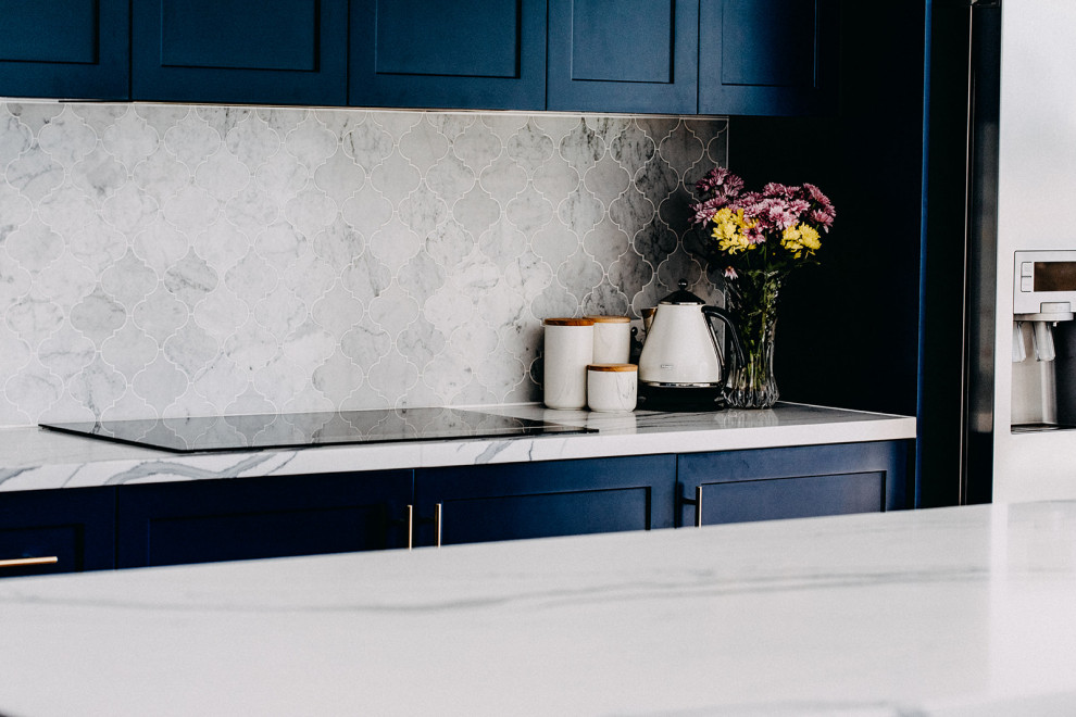 Inredning av ett klassiskt stort kök, med en undermonterad diskho, skåp i shakerstil, blå skåp, stänkskydd i marmor, ljust trägolv och en köksö
