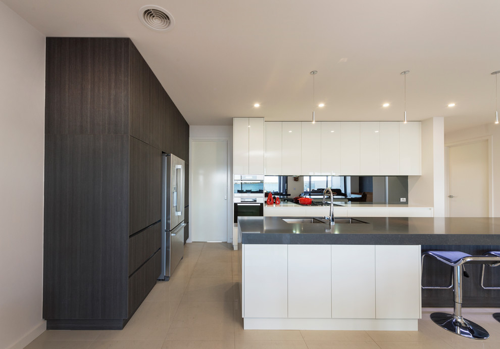 Kitchen - large modern ceramic tile kitchen idea in Melbourne with an undermount sink, flat-panel cabinets, white cabinets, gray backsplash, glass sheet backsplash, stainless steel appliances and an island