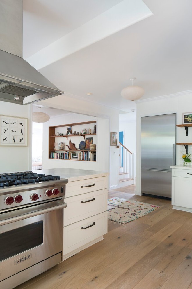 Inspiration pour une cuisine traditionnelle avec un évier de ferme, un placard à porte shaker, des portes de placard blanches, plan de travail en marbre, une crédence blanche, une crédence en carrelage métro, un électroménager en acier inoxydable, parquet clair et îlot.