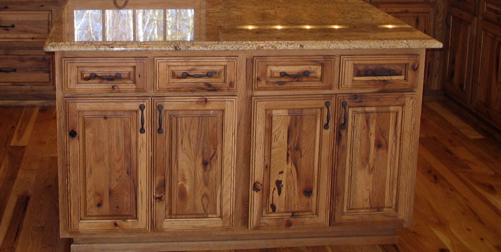 Ejemplo de cocina rural con armarios con paneles lisos, puertas de armario de madera oscura, electrodomésticos de acero inoxidable y suelo de madera en tonos medios