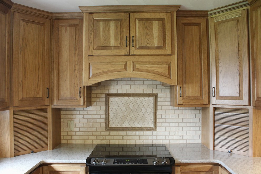 Bild på ett avskilt, mellanstort lantligt u-kök, med en undermonterad diskho, luckor med upphöjd panel, skåp i mellenmörkt trä, bänkskiva i kvarts, beige stänkskydd, stänkskydd i stenkakel, rostfria vitvaror och vinylgolv