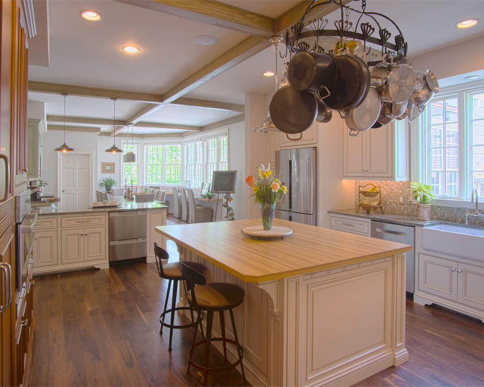 Foto på ett stort vintage kök, med en rustik diskho, luckor med infälld panel, vita skåp, rostfria vitvaror, mellanmörkt trägolv, en köksö, granitbänkskiva, stänkskydd i keramik, brunt golv och flerfärgad stänkskydd