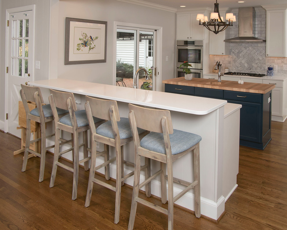Mid-sized transitional u-shaped medium tone wood floor and brown floor eat-in kitchen photo in Other with an undermount sink, recessed-panel cabinets, white cabinets, quartz countertops, gray backsplash, marble backsplash, stainless steel appliances and an island
