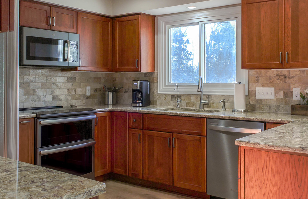Example of a mid-sized transitional u-shaped light wood floor and brown floor eat-in kitchen design in Detroit with an undermount sink, recessed-panel cabinets, medium tone wood cabinets, quartz countertops, beige backsplash, stone tile backsplash, stainless steel appliances, no island and beige countertops