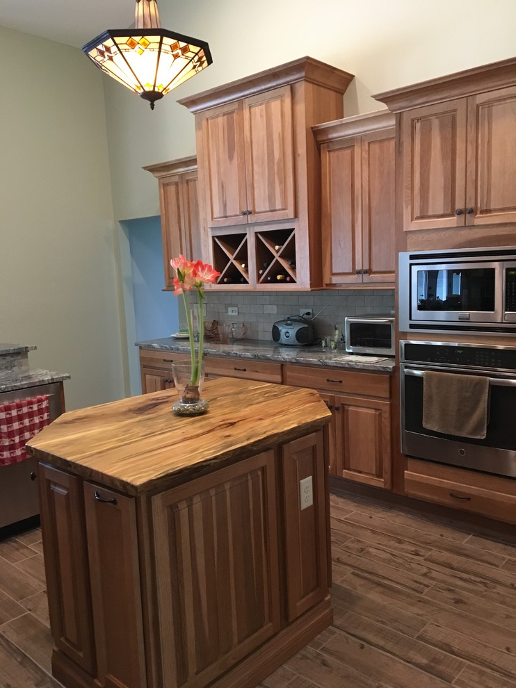 Kitchen - mid-sized farmhouse beige floor kitchen idea in Orlando with a farmhouse sink, light wood cabinets, granite countertops, stone tile backsplash, stainless steel appliances and an island