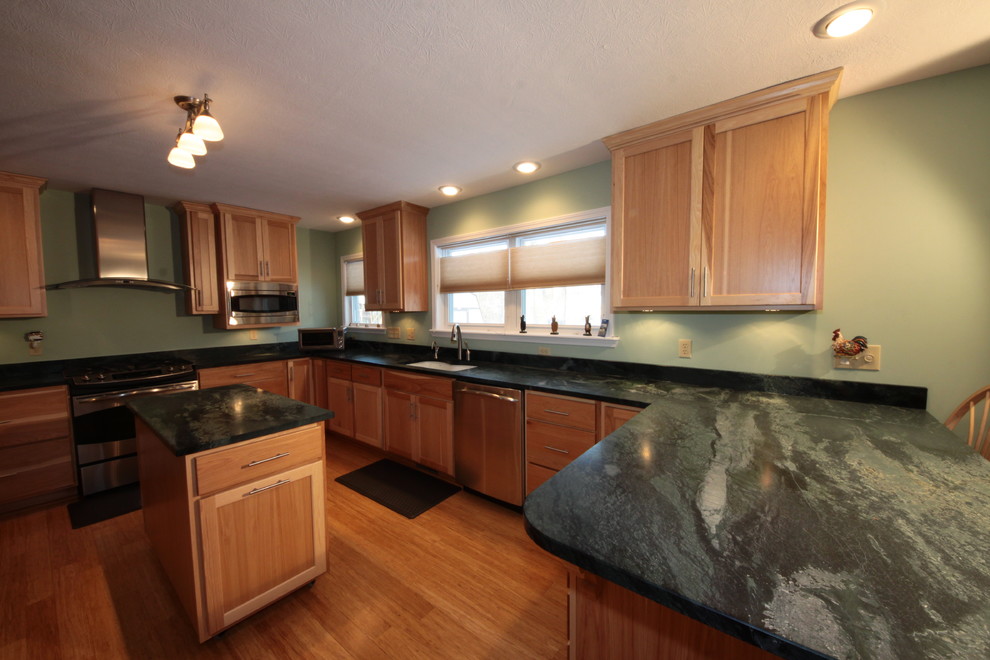 Bild på ett mellanstort lantligt kök, med en undermonterad diskho, skåp i shakerstil, skåp i ljust trä, granitbänkskiva, grönt stänkskydd, stänkskydd i sten, rostfria vitvaror, mellanmörkt trägolv och en köksö
