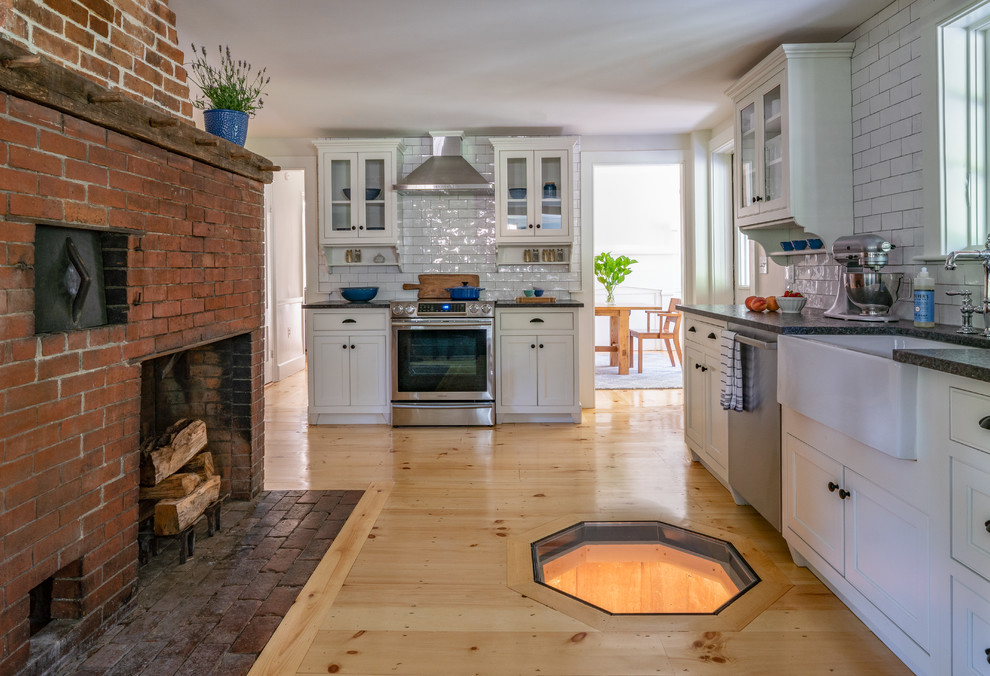 Mid-sized cottage l-shaped light wood floor eat-in kitchen photo in Boston with a farmhouse sink, white backsplash, beaded inset cabinets, white cabinets, granite countertops, subway tile backsplash, stainless steel appliances, an island and black countertops