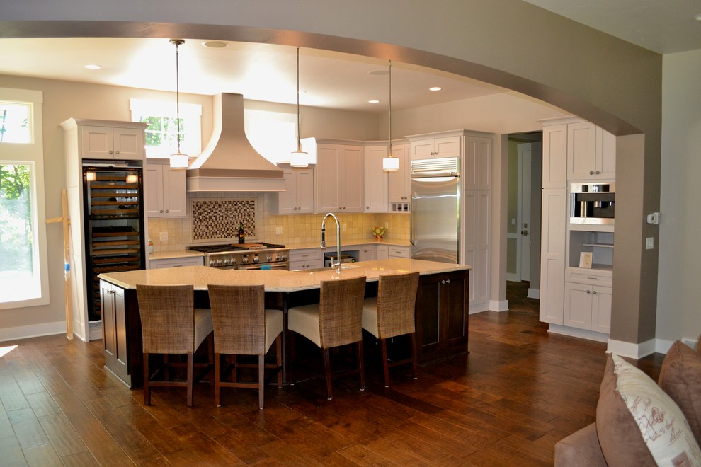 Inspiration for a large transitional l-shaped eat-in kitchen remodel in Milwaukee with an undermount sink, flat-panel cabinets, white cabinets, quartzite countertops, beige backsplash, porcelain backsplash, stainless steel appliances and an island