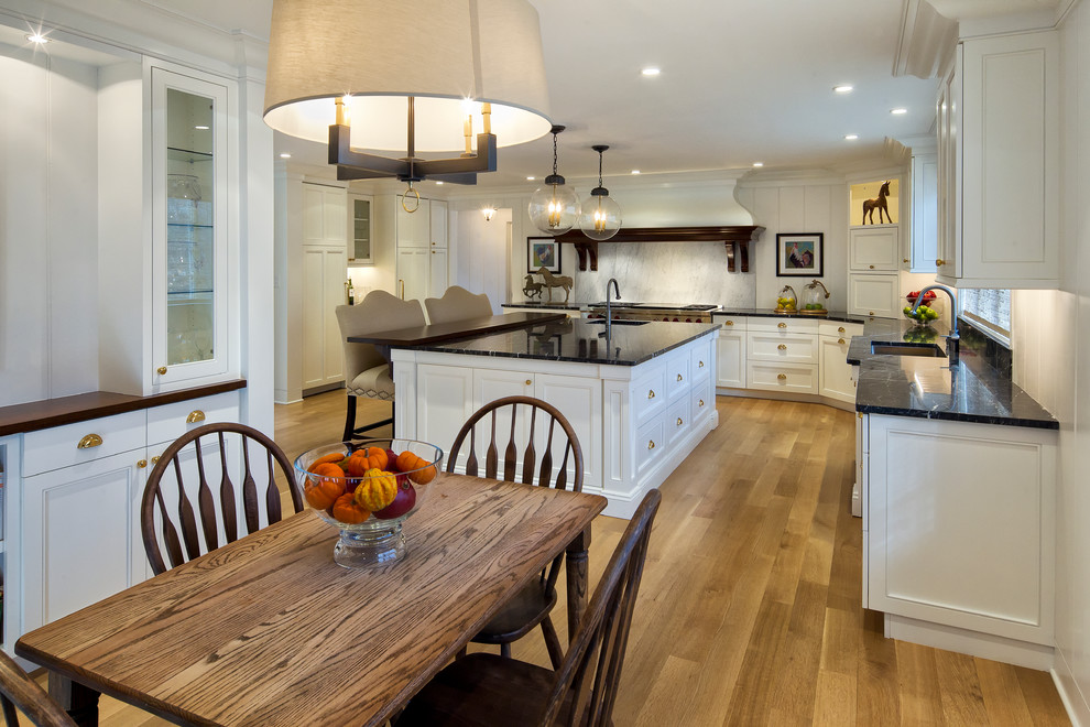 Eat-in kitchen - traditional l-shaped medium tone wood floor eat-in kitchen idea in New York with an undermount sink, white cabinets, granite countertops, white backsplash, beaded inset cabinets, marble backsplash, stainless steel appliances and an island