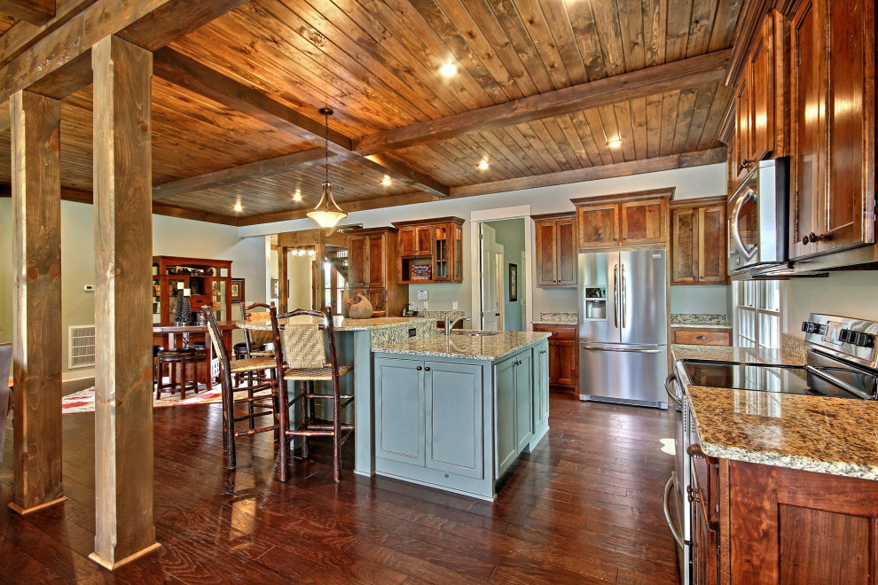Inredning av ett amerikanskt stort flerfärgad flerfärgat kök, med en undermonterad diskho, luckor med infälld panel, gröna skåp, granitbänkskiva, rostfria vitvaror, mörkt trägolv, en köksö och brunt golv