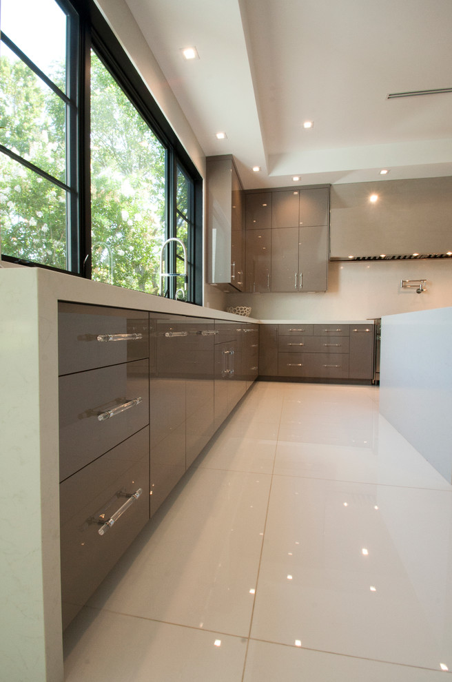 This is an example of an expansive modern u-shaped kitchen/diner in Los Angeles with a submerged sink, flat-panel cabinets, beige cabinets, composite countertops, stainless steel appliances, marble flooring and multiple islands.