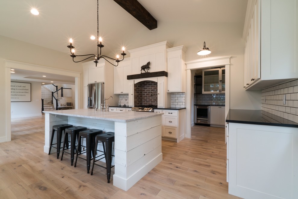 Photo of a rural kitchen in Minneapolis with white cabinets, white splashback and an island.