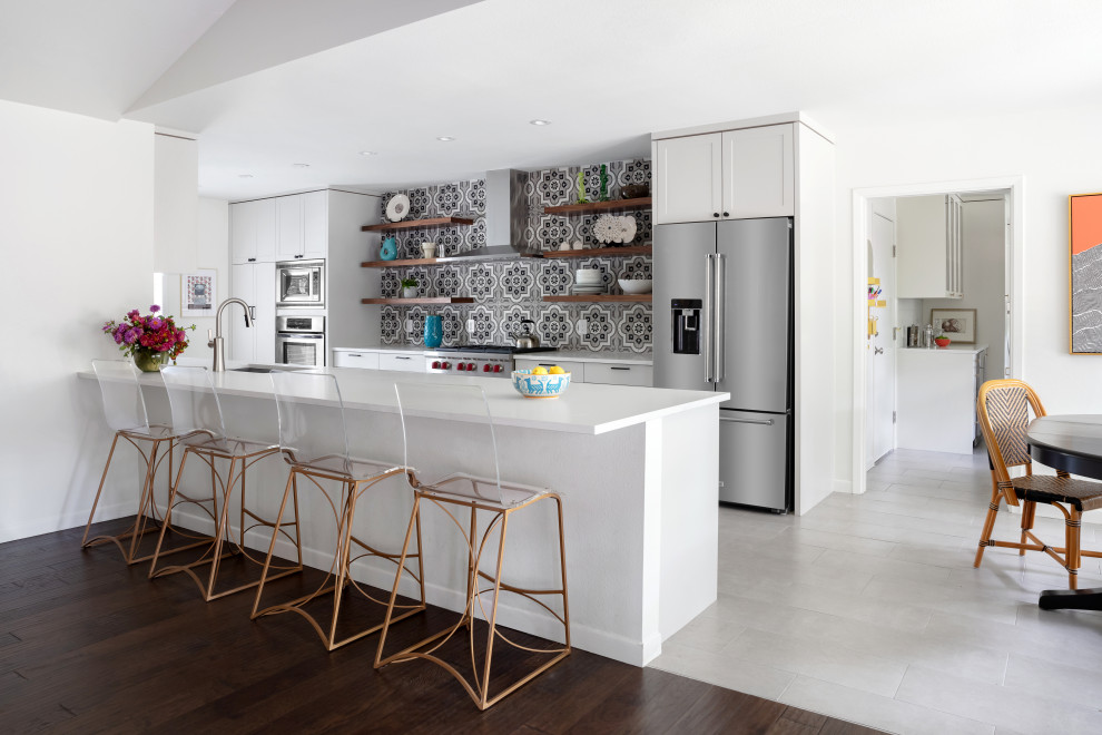 Bild på ett mellanstort funkis vit vitt kök, med en undermonterad diskho, skåp i shakerstil, vita skåp, bänkskiva i kvartsit, flerfärgad stänkskydd, stänkskydd i porslinskakel, rostfria vitvaror, en köksö och grått golv