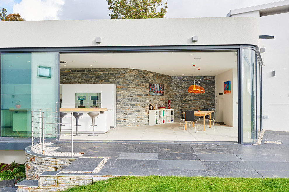 Moderne Wohnküche mit flächenbündigen Schrankfronten, weißen Schränken, Küchengeräten aus Edelstahl und Kücheninsel in Devon