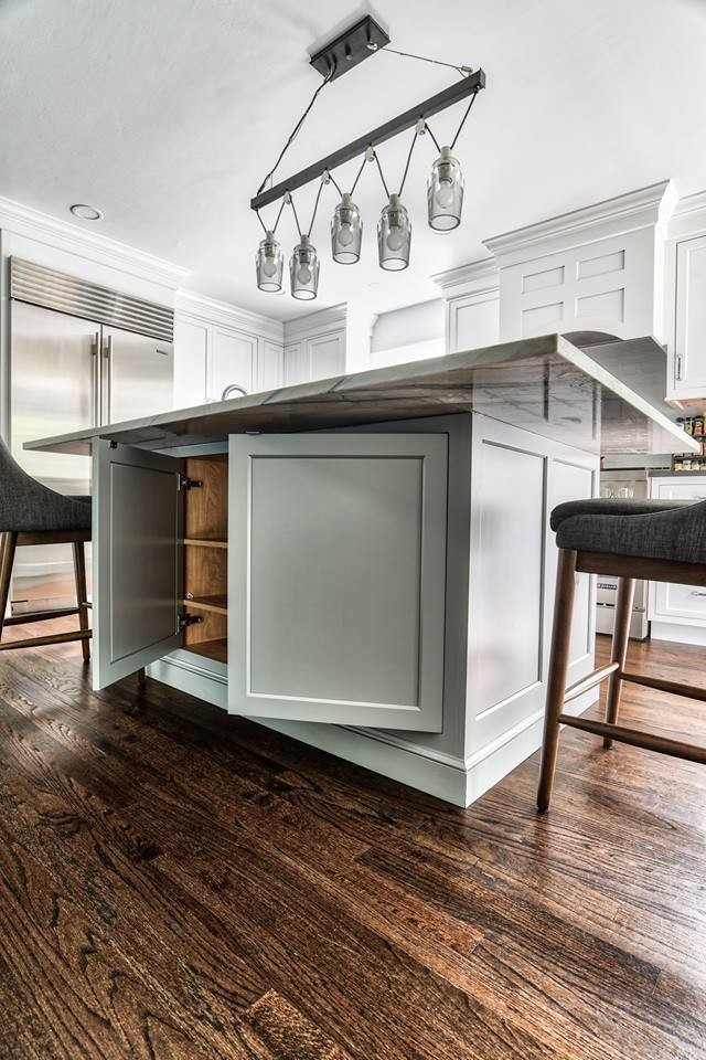 Example of a large transitional l-shaped medium tone wood floor and brown floor eat-in kitchen design in New York with a farmhouse sink, beaded inset cabinets, white cabinets, soapstone countertops, gray backsplash, subway tile backsplash, stainless steel appliances, an island and black countertops