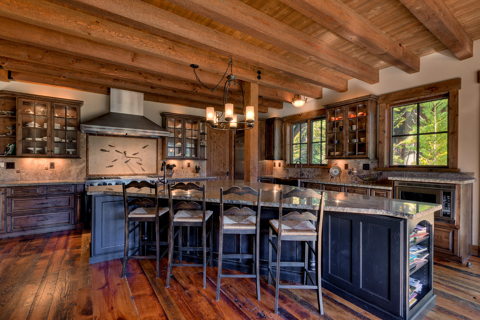 Example of a huge mountain style l-shaped medium tone wood floor and brown floor eat-in kitchen design in Sacramento with a farmhouse sink, raised-panel cabinets, multicolored backsplash, stainless steel appliances, an island, dark wood cabinets, granite countertops and ceramic backsplash