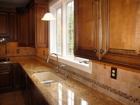 Medium sized classic l-shaped kitchen/diner in Philadelphia with a submerged sink, raised-panel cabinets, medium wood cabinets, granite worktops, brown splashback, stone tiled splashback, stainless steel appliances, porcelain flooring and an island.