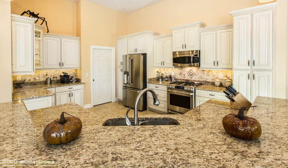 Open concept kitchen - large traditional u-shaped travertine floor open concept kitchen idea in Orlando with an undermount sink, raised-panel cabinets, white cabinets, granite countertops, multicolored backsplash, stone tile backsplash, stainless steel appliances and an island