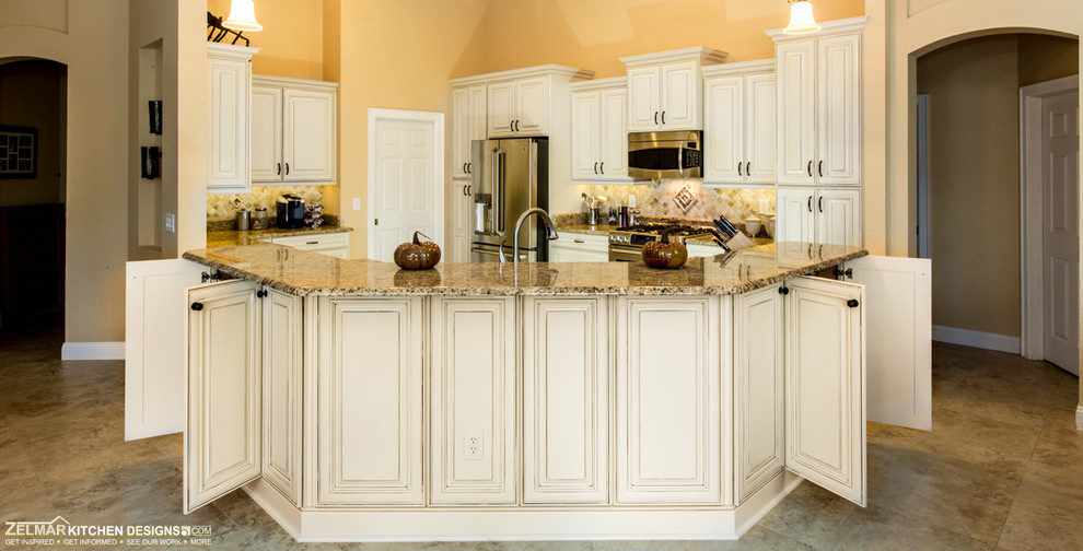 Foto på ett stort vintage kök, med en undermonterad diskho, luckor med upphöjd panel, vita skåp, granitbänkskiva, flerfärgad stänkskydd, stänkskydd i stenkakel, rostfria vitvaror, travertin golv och en köksö