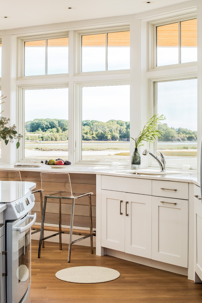 Immagine di una cucina stile marinaro di medie dimensioni con lavello sottopiano, ante in stile shaker, ante bianche, top in quarzo composito, pavimento in legno massello medio e paraspruzzi a finestra