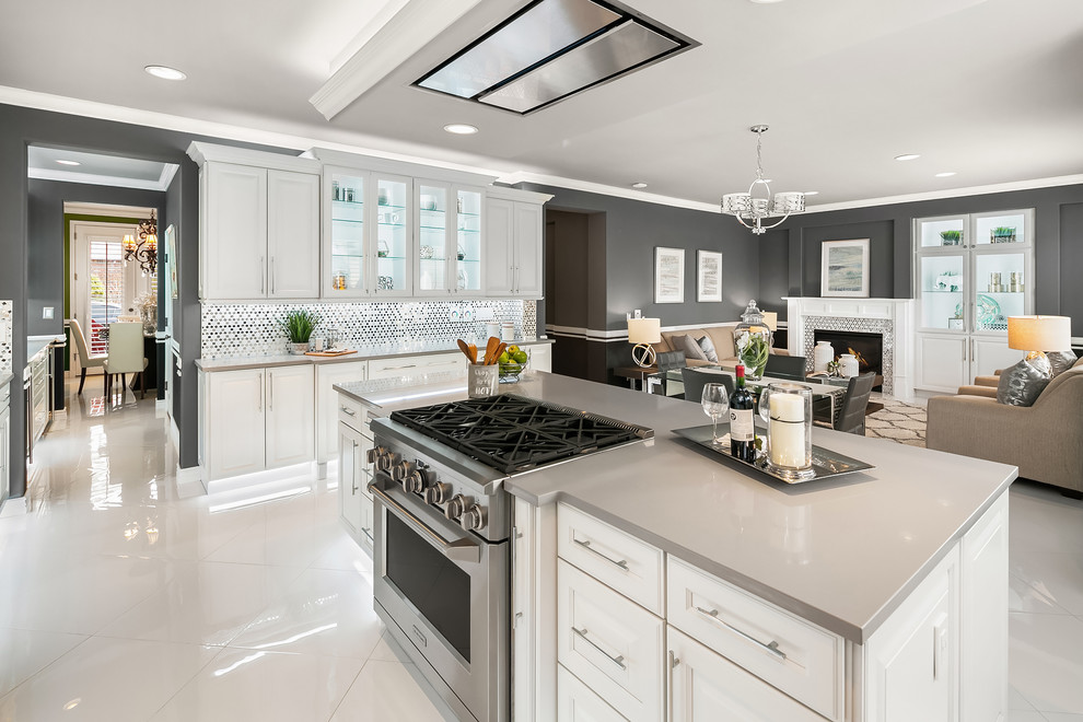 This is an example of a large classic l-shaped open plan kitchen in Seattle with a submerged sink, raised-panel cabinets, white cabinets, white splashback, stainless steel appliances, porcelain flooring, an island, white floors and grey worktops.