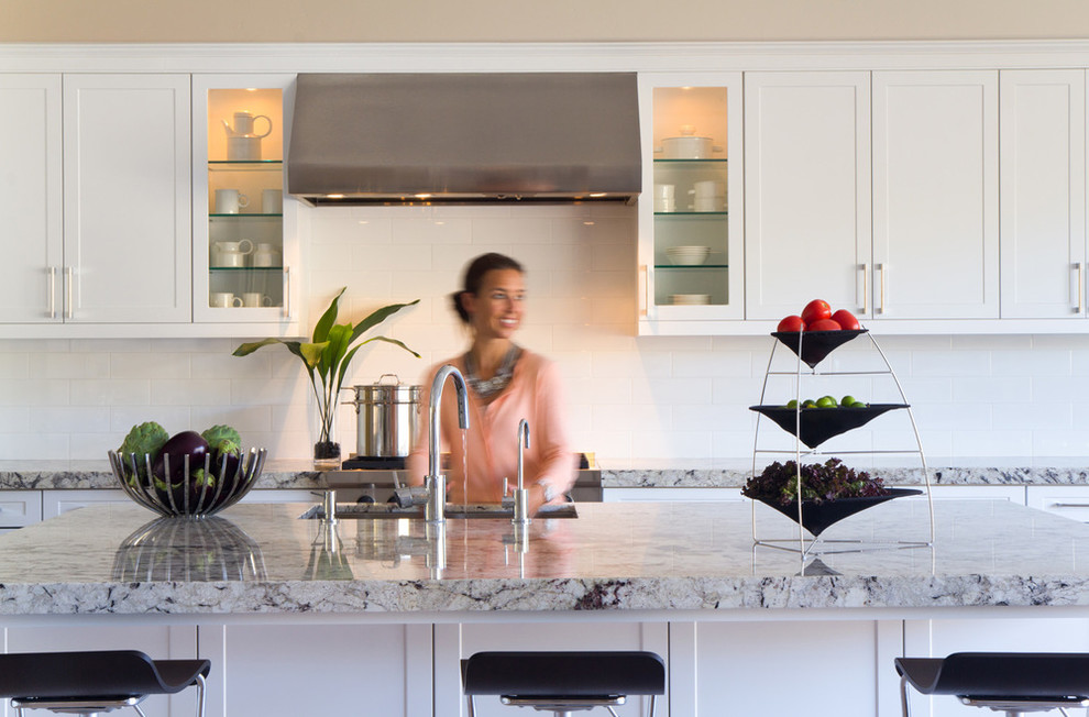 Klassisk inredning av ett kök, med en undermonterad diskho, skåp i shakerstil, vita skåp, granitbänkskiva, vitt stänkskydd, stänkskydd i keramik, rostfria vitvaror och en köksö