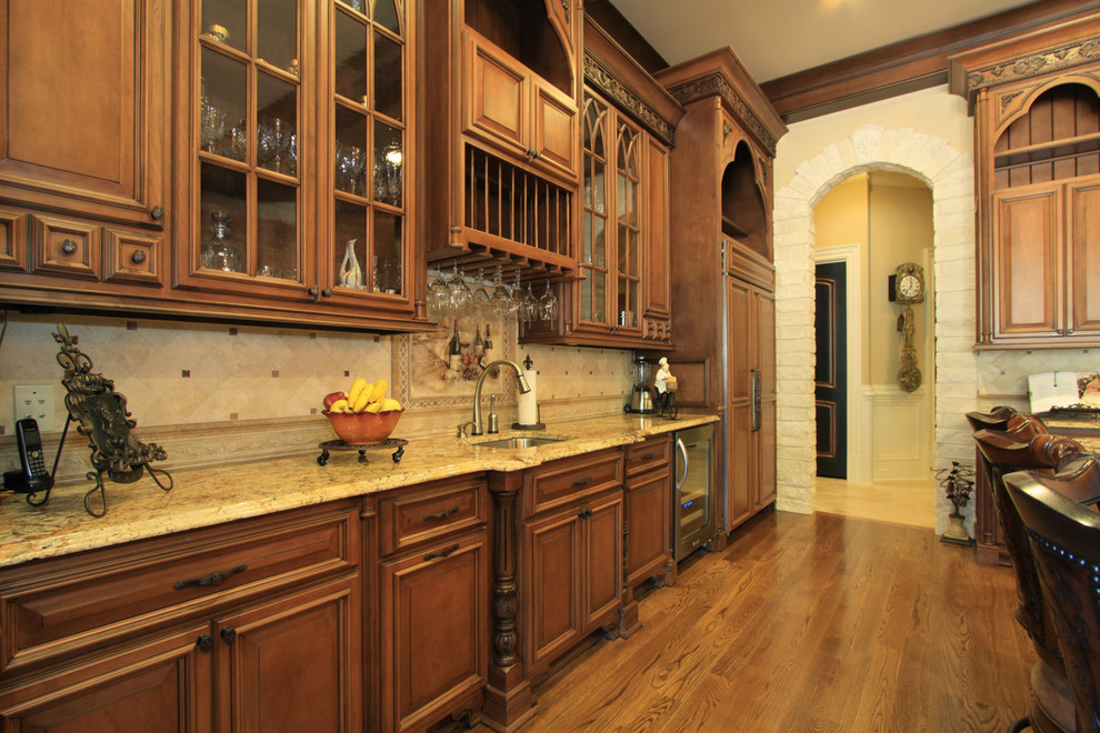 Example of a huge classic u-shaped medium tone wood floor eat-in kitchen design in Atlanta with an undermount sink, raised-panel cabinets, medium tone wood cabinets, granite countertops, beige backsplash, stone tile backsplash, stainless steel appliances and an island