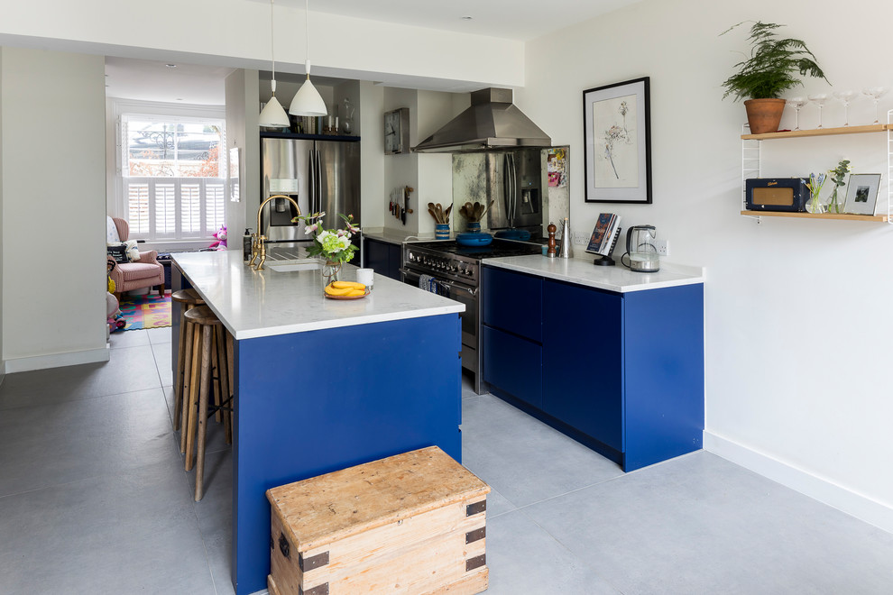 Inspiration for a large classic single-wall kitchen pantry in London with a built-in sink, recessed-panel cabinets, blue cabinets, granite worktops, mirror splashback, stainless steel appliances, ceramic flooring, an island and grey floors.