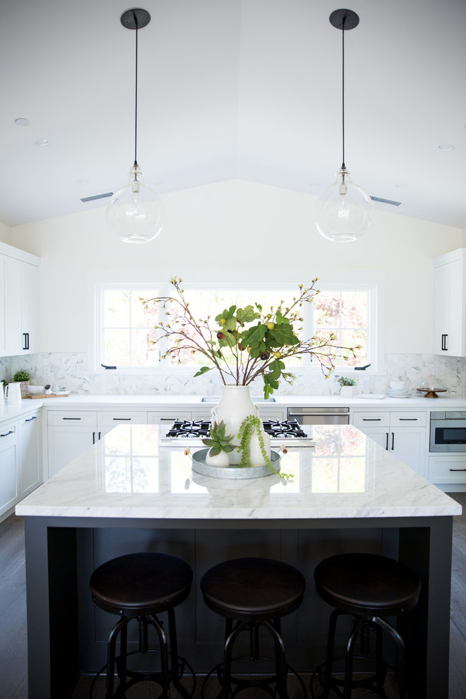 Foto på ett lantligt kök, med en undermonterad diskho, skåp i shakerstil, vita skåp, marmorbänkskiva, stänkskydd i mosaik, rostfria vitvaror, mellanmörkt trägolv och en köksö