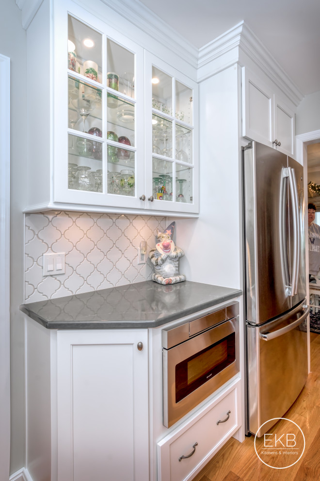 Small elegant galley light wood floor and brown floor enclosed kitchen photo in New York with an undermount sink, recessed-panel cabinets, white cabinets, soapstone countertops, white backsplash, ceramic backsplash, stainless steel appliances, no island and gray countertops