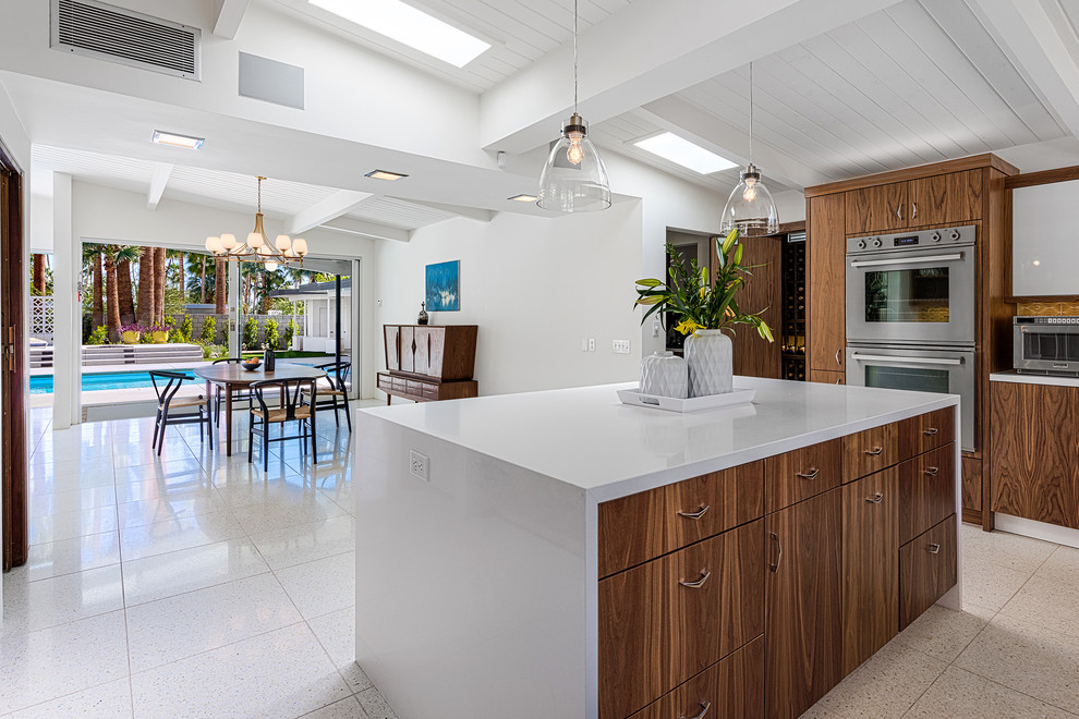 Mid-sized 1960s u-shaped eat-in kitchen photo in Other with flat-panel cabinets, medium tone wood cabinets, quartzite countertops, yellow backsplash, ceramic backsplash, stainless steel appliances, an island and a farmhouse sink