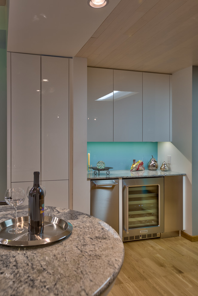 Immagine di una cucina minimal di medie dimensioni con lavello sottopiano, ante lisce, ante bianche, top in granito, paraspruzzi blu, elettrodomestici bianchi e parquet chiaro