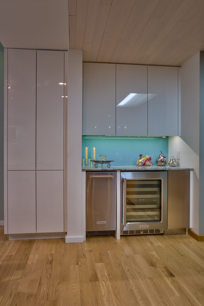 Foto di una cucina minimal di medie dimensioni con lavello sottopiano, ante lisce, ante bianche, top in granito, paraspruzzi blu, elettrodomestici bianchi e parquet chiaro